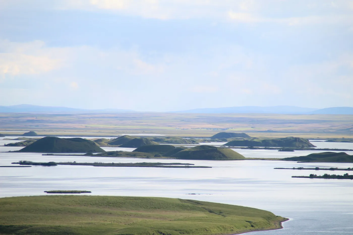 Green crater-shaped islets scattered across a wide lake under a pale sky